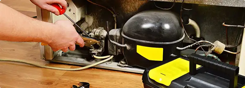 Refrigerator repair technician fixing the compressor and wiring in Mogadore, OH