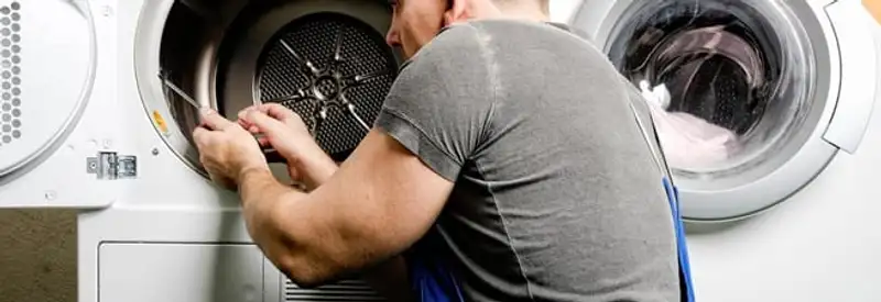 Dryer repair technician fixing a clothes dryer drum in Akron, OH