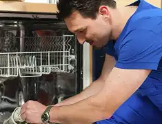 Dishwasher repair technician inspecting and servicing an open dishwasher in Akron, OH