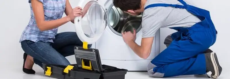 Washer repair technician inspecting a front-load washing machine with tools in Akron, OH