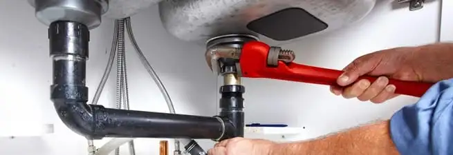 Garbage disposal repair technician tightening the sink drain and disposal connection in Akron, OH