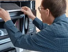 Appliance repair technician replacing a microwave vent filter in Akron, OH
