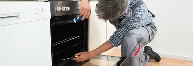 Oven repair technician inspecting and servicing an electric oven in Akron, OH
