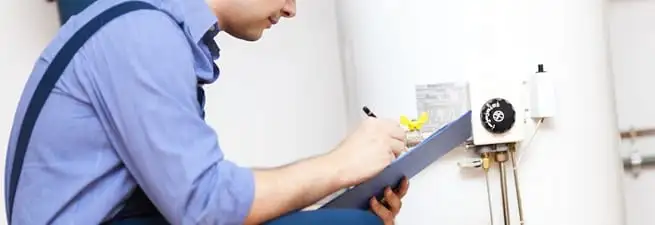 Water heater repair technician inspecting the unit and recording service notes in Akron, OH