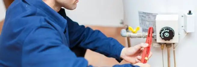 Water heater repair technician adjusting the temperature control and gas valve in Akron, OH